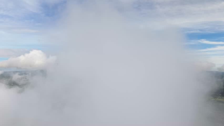 Aerial view of a majestic merapi mountain peak shrouded in clouds, surrounded by lush green landscapes and a serene sky, Klaten Regency, Central Java, Indonesia.