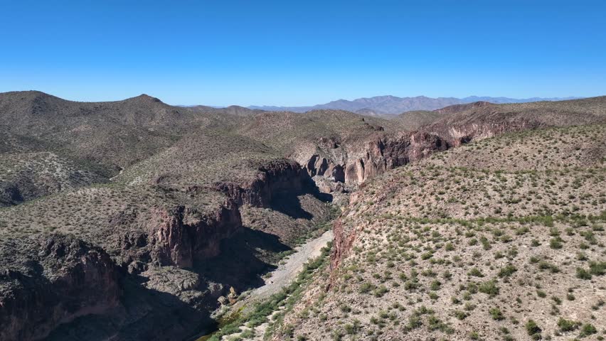 Aerial view of the rugged Burro Creek campground, where the ochre canyon walls meet a ribbon of green vegetation, Wikieup, Arizona, United States.
