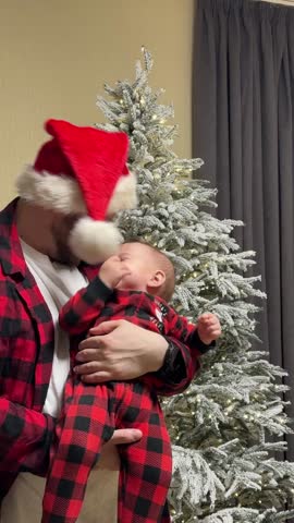 Father and Baby in Matching Pajamas by Christmas Tree.