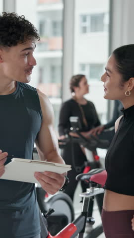 Gym, membership and people with clipboard, talking and explaining info for fitness class or session. Happy, woman and listening to man with checklist for registration, personal trainer and sign up