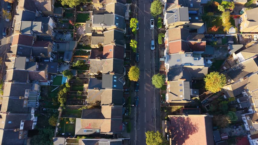 Aerial top-down drone flight over Francis Road, Leyton, London. The drone follows the road showing Victorian houses, gardens, 20 mph road markings, and red car travelling along the residential road.