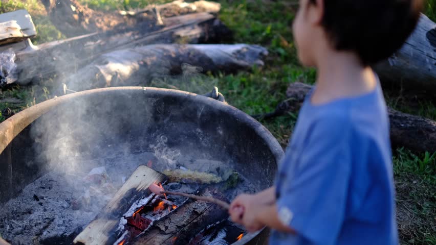 Family camping in yosemite, children and parent roasting marshmallows over a smoky campfire, sharing a sweet snack and creating memories outdoors	