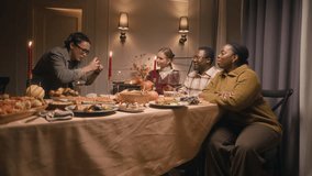 Long shot of young Asian man taking photos of diverse friends on mobile phone while dining together on Thanksgiving Day at home - Powered by Shutterstock - Get 15% off with code: PIKWIZARD15