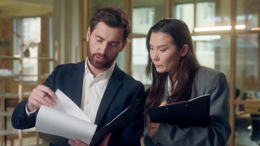 Multiracial office business workers speaking paperwork contract financial deal at office Caucasian businessman Korean businesswoman discuss chart lawyers documents agreement checking report indoors - Powered by Shutterstock - Get 15% off with code: PIKWIZARD15