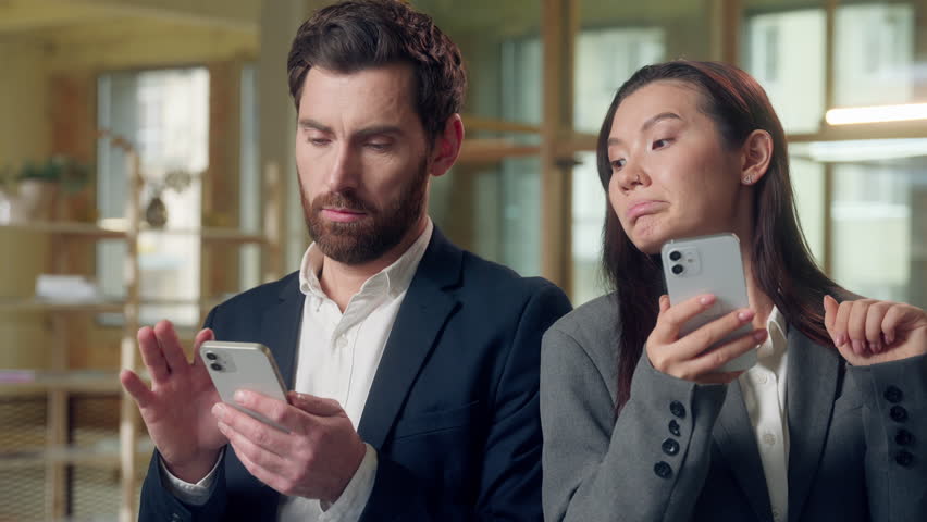 Multiethnic business colleagues using devices at office Korean businesswoman scrolling mobile phone thoughtful envious glancing coworker screen Caucasian man checks online networking browsing internet - Powered by Shutterstock - Get 15% off with code: PIKWIZARD15