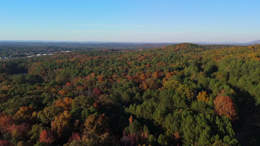 Drone footage of fall foliage covering rolling hills and forests near Anniston, Alabama. Vibrant autumn colors and layered terrain create a peaceful Southern landscape.