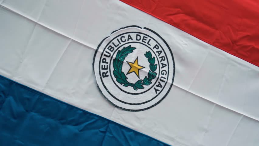 A detailed close-up of the national emblem of Paraguay displayed on a flag. The emblem represents the country's identity, history, and cultural heritage in detail.