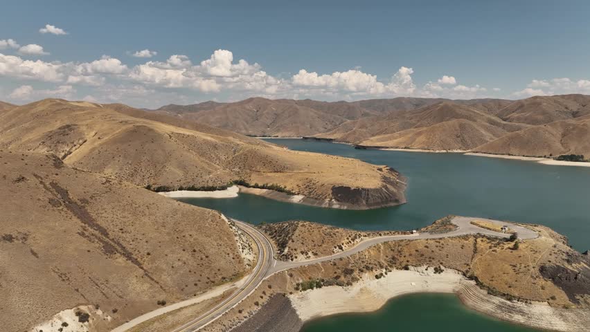 Aerial of Boise Reservoir with dry mountains, blue sky, and fluffy clouds