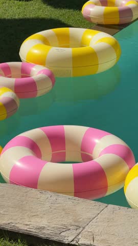 Close-up of bright vintage-style inflatable rings floating on clear water, capturing a chic Dolce Vita summer vibe with luxury, color, and playful poolside elegance