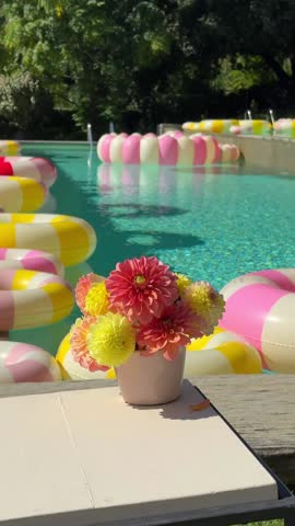 Close-up of a chic pool area with bright vintage-style inflatable rings floating on clear water, evoking a Dolce Vita luxury lifestyle and elegant summer relaxation