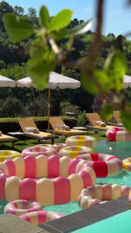 chic villa terrace in Tuscany with bright pools, yellow-white towels on sun loungers, vintage-style inflatable rings, umbrellas, and a Dolce Vita after-wedding party vibe
