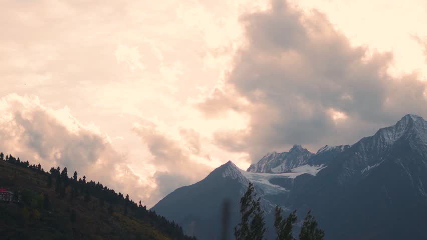 Landscape shot of orange clouds above the snowy Himalayan mountain peak during the sunset as seen from Keylong in Lahaul and Spiti district, Himachal Pradesh, India. Scenic view of sunset in autumn.