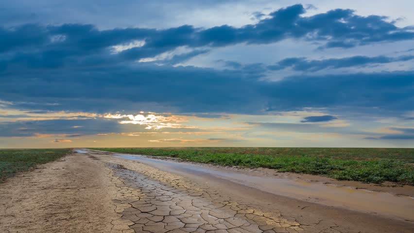 ground road throgh the green prairie at the dramatic sunset time lapse scene