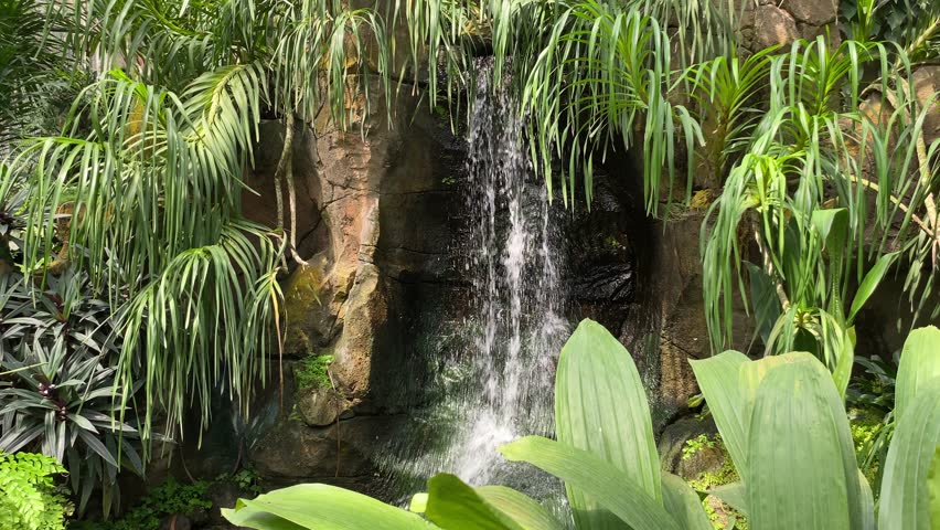 Water splashed from garden waterfall decorations in a indoor park, surrounded by green plants