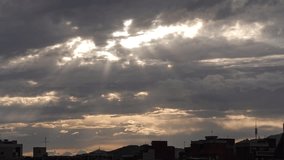Dramatic sky with dark clouds and rays of sunlight breaking through. Urban skyline silhouette at dusk. Atmospheric and moody scene. - Powered by Shutterstock - Get 15% off with code: PIKWIZARD15