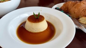 Caramel custard pudding served on a white plate with caramel sauce and croissant in the background - Powered by Shutterstock - Get 15% off with code: PIKWIZARD15