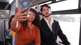 Happy young multiracial couple taking a selfie with a smartphone while traveling together on a public bus, sharing a moment of fun - Powered by Shutterstock - Get 15% off with code: PIKWIZARD15