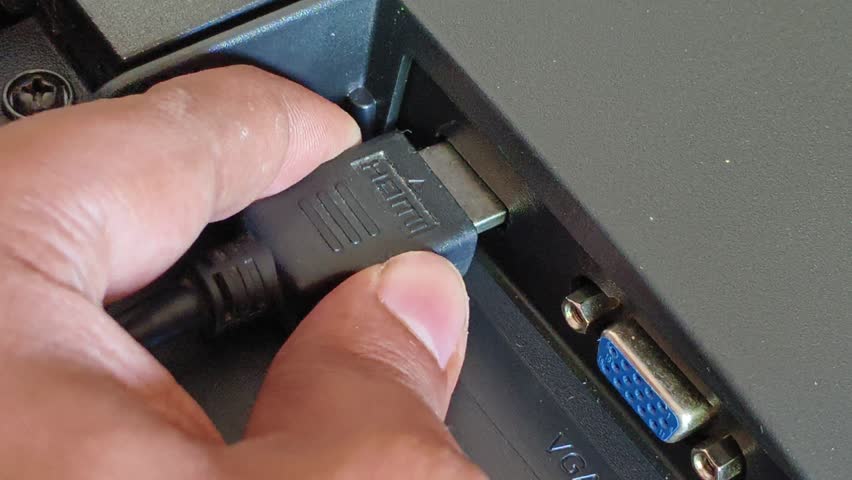 Hand plug, insert, input or connect a HDMI cable cord into a monitor device port or socket hole. Close up macro top view. High definition video and audio multimedia technology concept.	