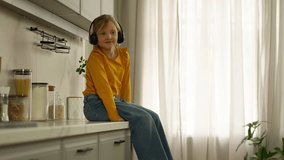 Little Caucasian child kid girl listening music in headphones sitting on table at home kitchen daughter baby relaxing listen song audio in modern earphones technology gadget enjoying sound having fun - Powered by Shutterstock - Get 15% off with code: PIKWIZARD15
