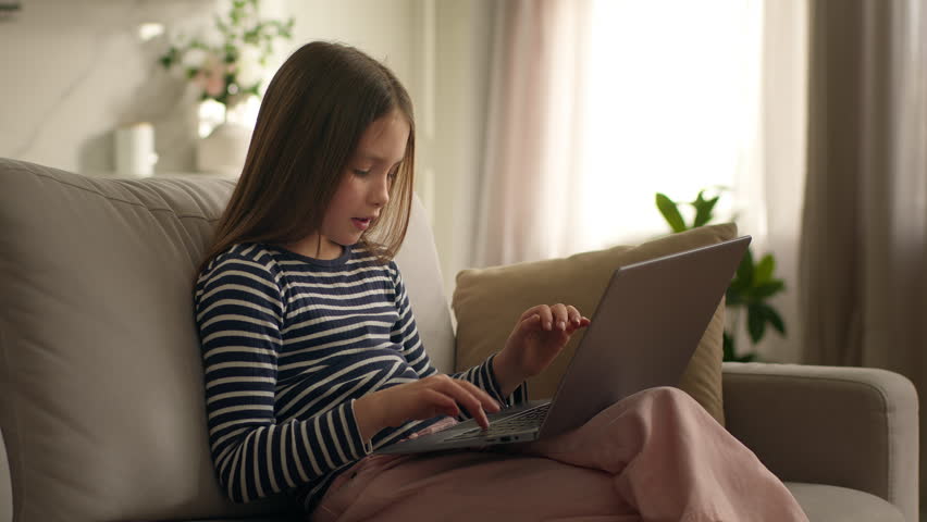 Caucasian child kid girl using laptop computer pc technology at home smiling laughing typing message chatting texting communicate online web chat at couch gadget addict generation e-learning daughter - Powered by Shutterstock - Get 15% off with code: PIKWIZARD15