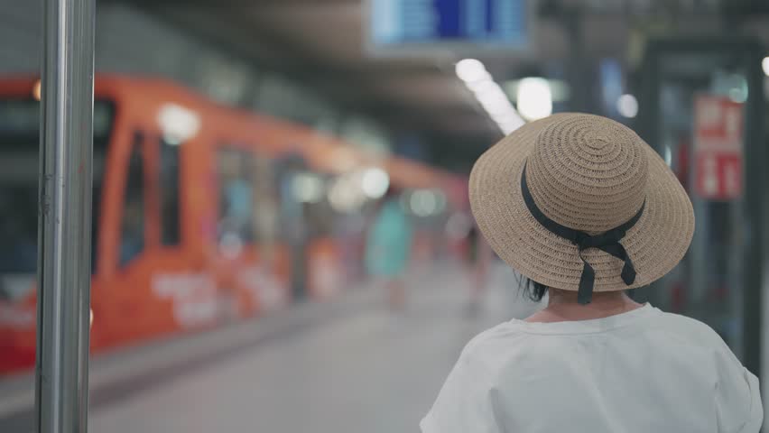 Business woman traveler sitting on underground metro station waiting for fast electric train arriving at background, slow motion shot with selective focus