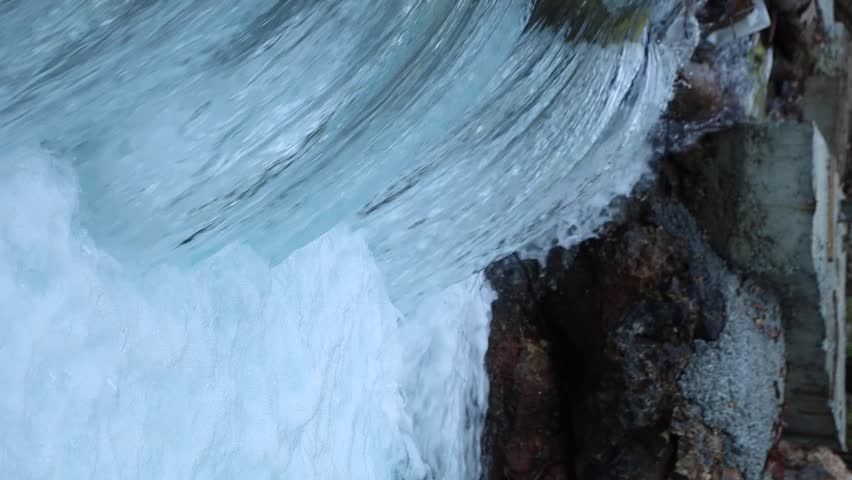 Close-up of powerful waterfall stream crashing over rocks, white foam and smooth flowing water texture in wild nature, energetic clean river scene for relaxation and nature background