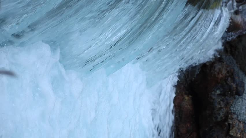 Close-up of powerful waterfall stream crashing over rocks, white foam and smooth flowing water texture in wild nature, energetic clean river scene for relaxation and nature background