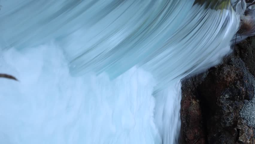 Close-up of powerful waterfall stream crashing over rocks, white foam and smooth flowing water texture in wild nature, energetic clean river scene for relaxation and nature background