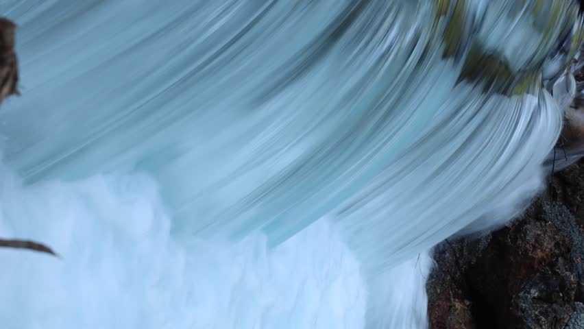 Close-up of powerful waterfall stream crashing over rocks, white foam and smooth flowing water texture in wild nature, energetic clean river scene for relaxation and nature background