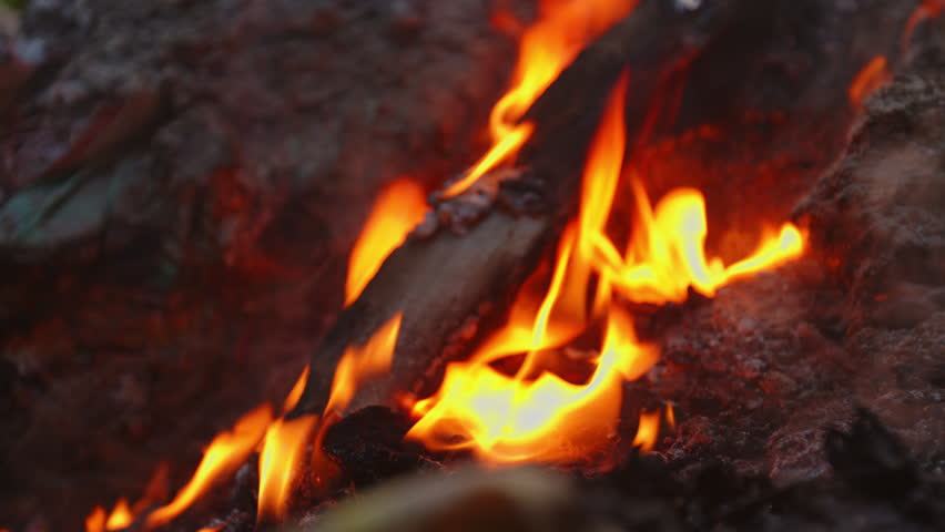 Burning plastic waste with rising smoke on soil in an open outdoor environment. Shows environmental pollution, toxic fumes, air and soil contamination, and waste management issues. Captured in natural