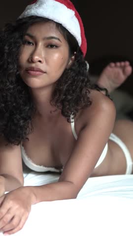 Vertical View of Sexy Asian Woman With Santa Hat and White Lingerie Lying on Bed