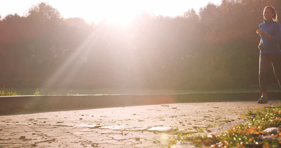 Caucasian man and woman running together. Tired after long physical activity. Stopping to rest after jogging. Smiling from joy after working out. Girl with earphones. Music in earphones.