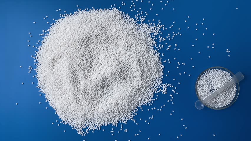 A scientist in a laboratory in blue gloves checks the quality of a batch of white thermoplastic granules. Concept: research, biochemistry, pharmaceutical medicine, plastics plant. Slow motion.