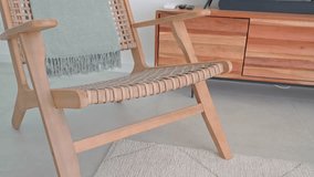 Light green throw blanket draped over a wooden armchair with woven seat in a contemporary living room setting, featuring a wooden media console and a large screen television - Powered by Shutterstock - Get 15% off with code: PIKWIZARD15