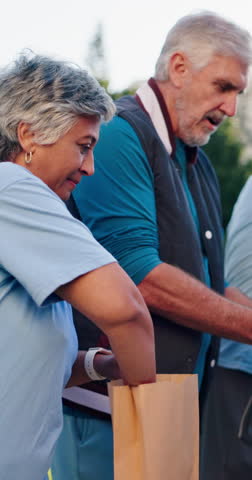 Senior woman, packing bag and volunteer with food drive, group and help for social responsibility at park. Mature people, team and accountability with care, smile and support for ngo at charity event