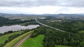 Aerial drone view of railway disappearing into tunnel beneath high-speed overpass, showing layered transport infrastructure, perspective depth, and striking contrast of motion corridors. - Powered by Shutterstock - Get 15% off with code: PIKWIZARD15