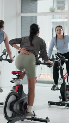 Spin class, cardio and women on bike, fitness and training routine for physical activity and health. Gym, personal trainer and people on machine for body strength, mobility and cycle for wellness