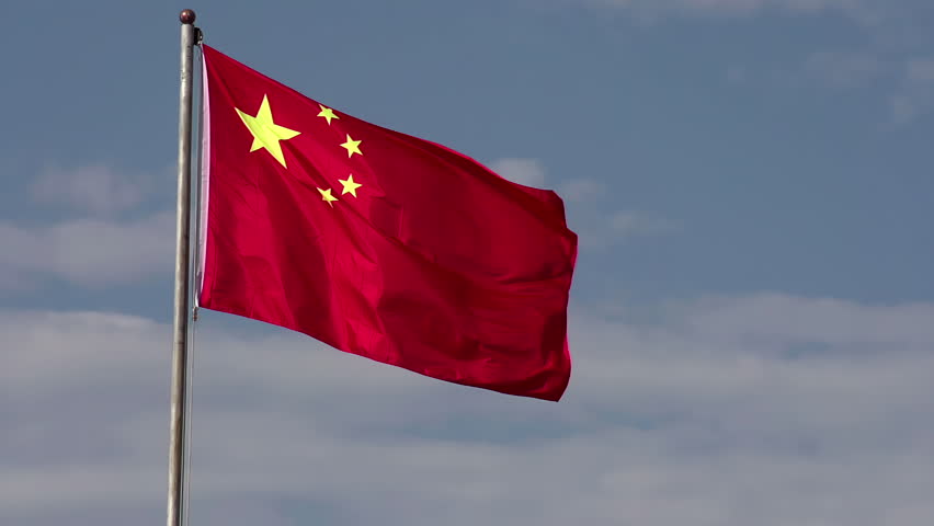 Waving Chinese Flag. Flag of the People's Republic of China against the blue sky with white clouds. Slow Motion