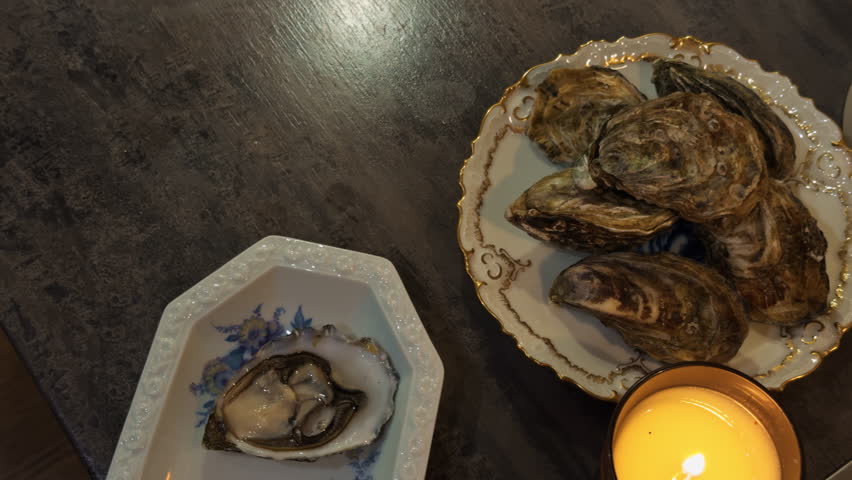 Gathering oysters during intimate dinner, Hand picks oyster as candlelight flickers softly - Powered by Shutterstock - Get 15% off with code: PIKWIZARD15