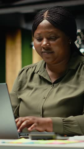 Vertical Video Excited beaming black woman receiving good news for an opportunity, woman being proud of breakthrough and accomplishment in the office after hours. Delighted about contract deal. Camera