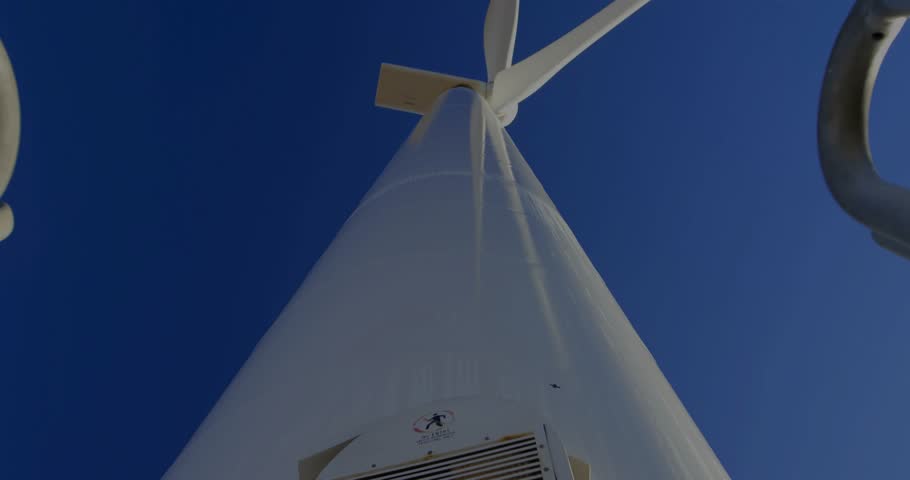 Technician pulling hatch handles at wind turbine, lowering panel for safety check with code overlay. Tower, rotor, blade, ladder, doorway, maintenance, worker