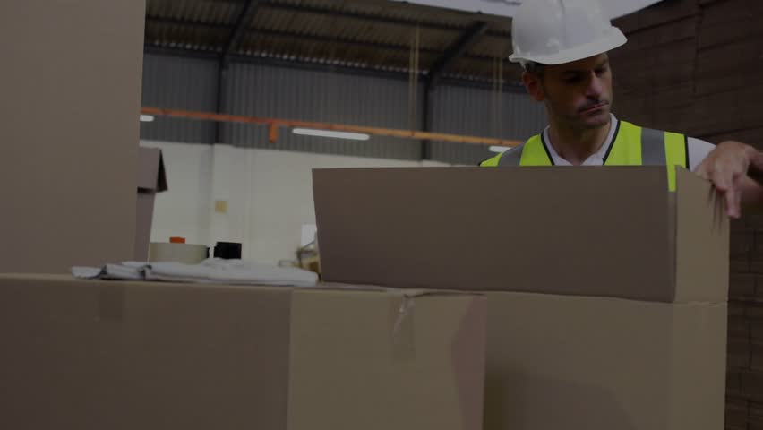Warehouse packer inspecting box, grabbing tape dispenser, sealing for shipping, HUD tracking hands. Packaging, fulfillment, logistics, warehouse, worker, hardhat, highvis