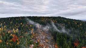 Gentle fog rides over rocky woods during fall day, Dense mist hovers above stone outcrop amidst forest with autumn hues - Powered by Shutterstock - Get 15% off with code: PIKWIZARD15