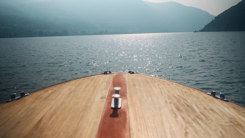Static shot of a wooden speed boat navigating over blue water at Lake Iseo, Italy (Lago d’Iseo), near Montisola, Isola di Loreto, and Isola di San Paolo