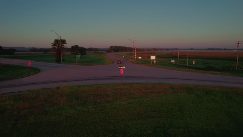 A cattle trailer and classic semi idle at sunrise along the interstate ramp. Golden light, rolling farmland, quiet Midwestern morning.