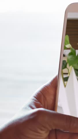 Animation of person using smartphone with house kitchen interiors displayed on screen. Online shopping house decorating concept digital composite.