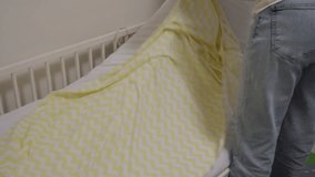 A Loving Preparation: Parent Gently Makes a Baby's Crib with a Cheerful Blanket. - Powered by Shutterstock - Get 15% off with code: PIKWIZARD15