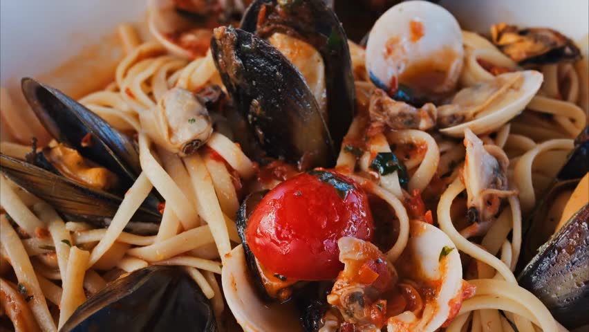 Close-up of pasta with seafood and tomato sauce on a restaurant plate, showcasing gourmet cuisine, fresh ingredients, and elegant dining presentation.
