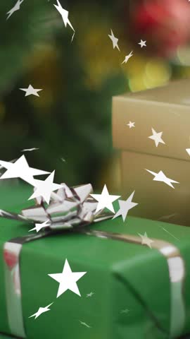 Animation of stars falling over christmas decorations and gift background. Christmas, festivity, celebration and tradition concept digitally generated video.