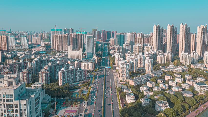 Aerial panoramic view of Wuhan city skyline showing modern skyscrapers, residential buildings, and urban development in South China with clear blue sky.